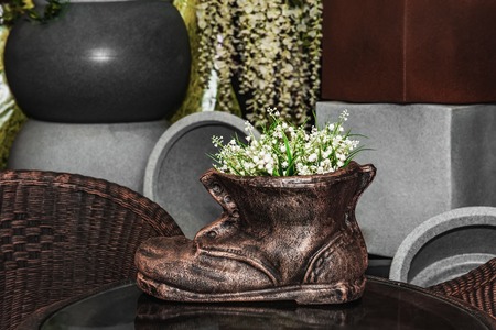 Flowerpot pots in a plastic or ceramic shoe lilies of the valley on the table in the store.