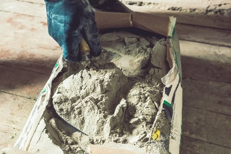 Cement powder in the cement bag, a hand hold the trowel scoop cement powder cray for construction work.の写真素材