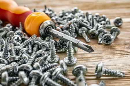 Manual screwdriver screws and dowels on a wood background.の写真素材