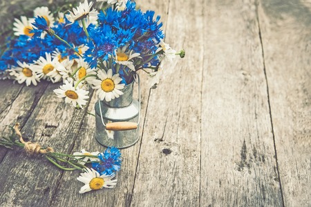 Bouquets of beautiful wild flowers of daisies and cornflowers on a wooden old background. Copy paste.の写真素材