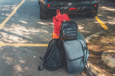 Black backpack and orange suitcase and other things are in the car. Luggage is built for travel.の写真素材
