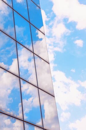 A skyscraper or modern building in a city with clouds and sunlight reflected in the Windows.の写真素材