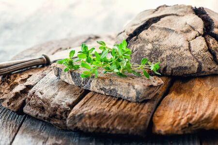 A piece of rye bread with a bunch of thyme on a wooden old stand. Farmers early Breakfast