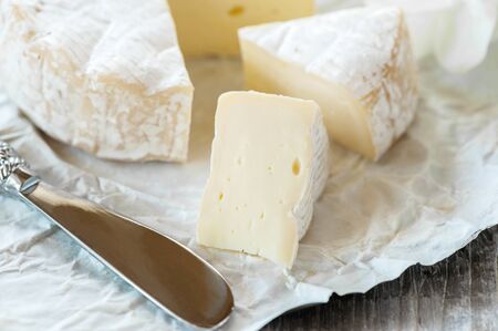 Gourmet spicy Camembert cheese, brie on white paper background with cheese knife. Spicy appetizer for gourmets. Selective focusの写真素材