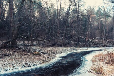 Winter landscape with sunset on the river Bank. The trees are covered with snow, the setting sun illuminates a beautiful mysterious landscape with a river and icy shores.の写真素材