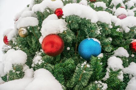 Christmas decor Christmas tree under the snow on the street. Big red and blue balls on the branch. Selective focus.の写真素材