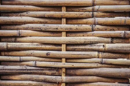 Fence made of woven dry bamboo in the Park. Natural braided background.の写真素材