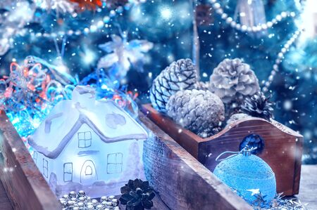 Festive Christmas decor. A luminous glass decorative transparent house lies in a box with Christmas tree needles for decorating the house and the Christmas tree.の写真素材