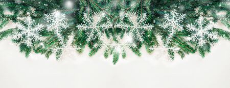 Christmas decorations. Frame of Christmas tree branch, and white shiny snowflakes on white background , Copy space. Selective focus. Banner.の写真素材
