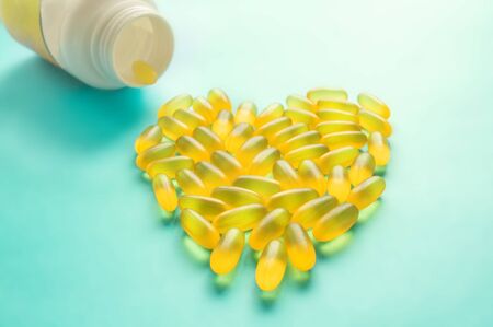 Large medical capsules and tablets-vitamins and food additives on a blue background lie in the shape of a heart. Copy space. Close up. Selective focus.の写真素材