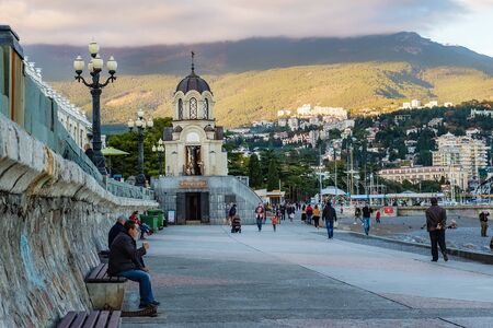 Yalta, Crimea-October 9, 2019: chapel in honor of St. Alexander Nevsky in Yalta. Warm Sunny autumn evening at sunset. People walk on the waterfrontのeditorial素材