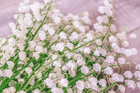 A large bouquet of lilies of the valley on a wooden table. Selective focus. Close up. Floral...