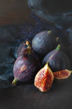 A juicy slice of Fig and a group of figs with lavender on a rustic blue wooden table close-up in a restrained key. Copy space.の写真素材