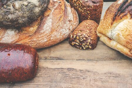assortment of baked bread on a wooden background. Different types of handmade bread on the table....