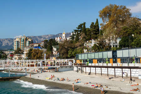 October 1, 2019 Yalta, Crimea View from Massandra beach on the West Bank of the city of Yalta in early autumn. People swim and sunbathe on the beach. Editorialのeditorial素材
