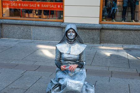 Oslo, Norway-may 26: an unknown MIME in a Silver suit performs on a street in Oslo on July 11, 2013 . Living statues entertaining the tourists. Beautiful girl in a hood.のeditorial素材