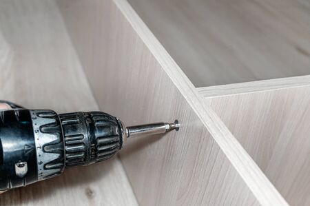 master collects furniture. Close-up of the master connecting the Cabinet parts. Concept of repair and renovation. copy space.の写真素材