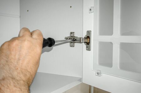 master collects kitchen furniture. Close-up of the master attaching the Cabinet doors. Concept of repair and renovation. copy place.の写真素材