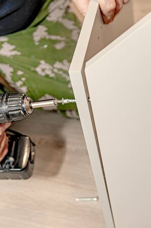 master builds a furniture Cabinet. Mounting for furniture panels. Assembling the Cabinet door mechanism.の写真素材