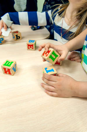 childs hands play in the constructor. The kid puts together wooden cubes. Selective focus. Copy of...