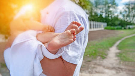 leg of a baby who is gently held in the hands of the father of a small child. Selective, soft focus....