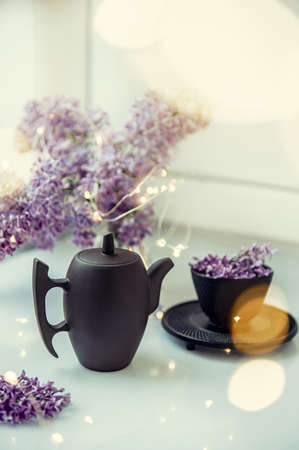 Cup of tea with lilac flowers on a light background. Mocap for postcards. Spring. Vase with lilac. Copy space. concept of holidays and good morning wishes.の写真素材