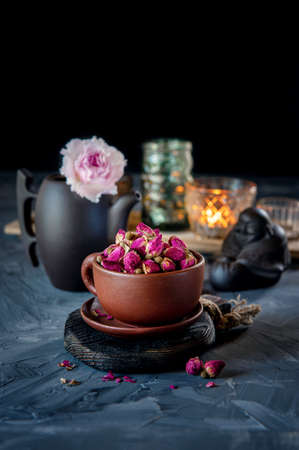 brown ceramic Cup of rosebud tea sits on a wooden table. Tea time, cozy atmosphere. Kitchen still life with tea from pink flowers with warm light in the background.の写真素材