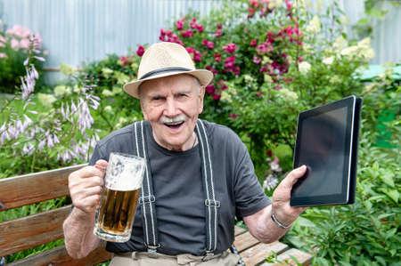 elderly man in a hat drinks beer outside the pub on a bench in the garden. An old man is working on...
