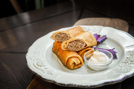 Pancakes stuffed with meat are served with Basil and cream sauce with sour cream. Restaurant meal. Close upの写真素材