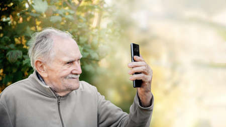 An elderly man looks at the camera talking and smiling.の写真素材