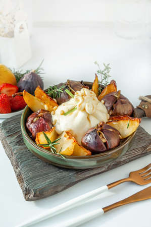 Buratta with caramelized pears and figs baked with honey. Pine nuts complement the dish. Copy space.