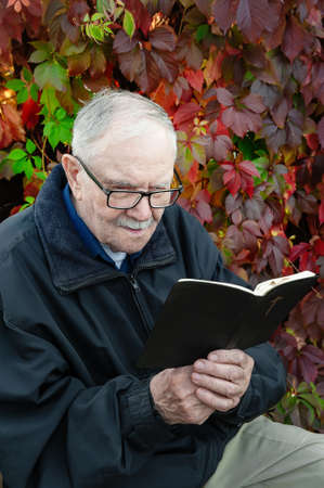 Healthy looking old man is his late 87s sitting in garden at home and reading book.の写真素材