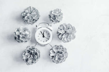 Christmas clock on a wooden wall with a Christmas tree and cones. Top view, copy space.