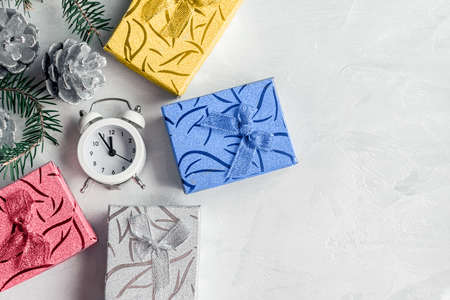 bunch of colorful Christmas gifts and new year's clock on a light uniform background top view. Copy...