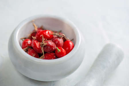 ripe rose hips in a stone mortar and pestle. Rosehip will be crushed to make vitamin tea. Copy spaceの写真素材