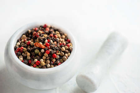 White porcelain mortar and pestle with hot red chili pepper and different types of peppers. Peppers...