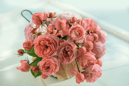 bouquet of pink English roses in a basket on a light table background. Close-up of rose buds, selective focus. Close up.の写真素材