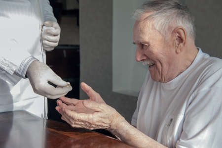 doctor gives a pill to an old man. The old man is ill and needs medicine. Geriatric care for the elderly.の写真素材