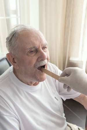 doctor looks inside the mouth of an elderly patient. The doctor examines an elderly patient. Close up.の写真素材