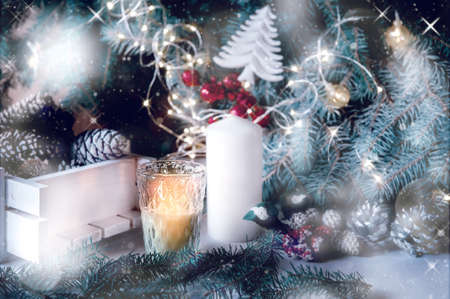 large white candle in a wicker holder under a Christmas tree. Christmas holiday design. decorated with garlands and glittering lights.の写真素材