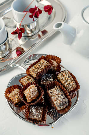 Handmade chocolate covered with cocoa and nut crumbs. Still life with sweets and tea appliances.