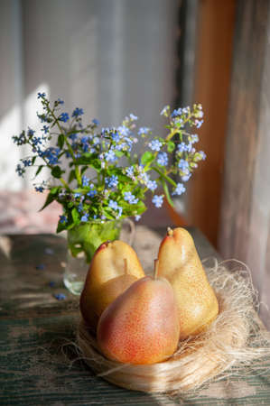 wicker metal fruit basket, on an old wooden background. Assorted pears, peaches and grapes on the table in the village.の写真素材