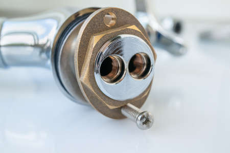 Not installed mixer with one handle kitchen faucet, side view of the base with holes for connecting the supply pipes close-up in selective focus.の写真素材