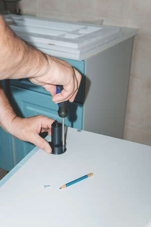 Installation of a plastic foot for the cabinet. the hand of a man repairing furniture in the house.の写真素材