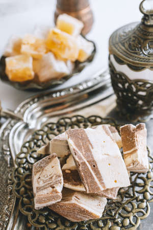 a vase with various pieces of halva and oriental sweets on a light background. Close-up of halva.の写真素材