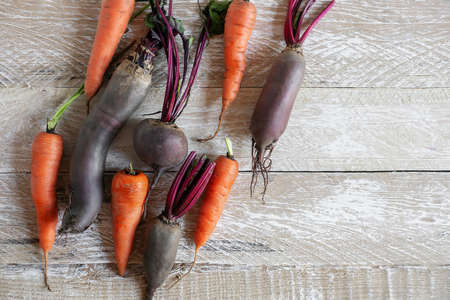 Set of bright colored vegetables on the table top view . Carrots and beets are laid out on a wooden...