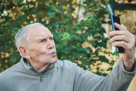 gray-haired, 88-year - old man with glasses happily counts his savings.の写真素材
