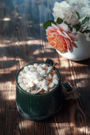 coffee with marshmallows. a delicious drink made of cocoa or hot chocolate with marshmallows in a cup on a wooden table. Still life in a rustic style with a beautiful openwork lightの写真素材