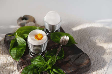 Open a soft-boiled egg in an egg cup. Homemade low-calorie breakfast with a spoon on a rustic table....