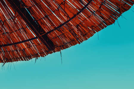 wicker umbrella by the sea, turquoise sea. symbol of travel and recreation on the seashore. sky, copy spaceの写真素材